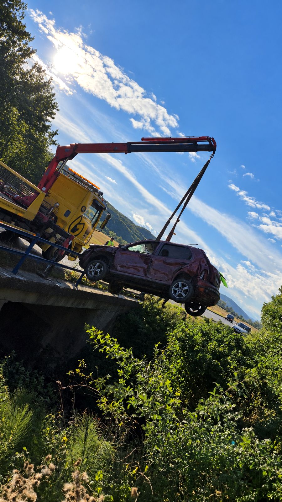 Vyťahovanie havarovaného auta žeriavom z mosta